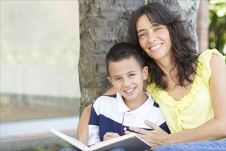 Hispanic mother and son reading book