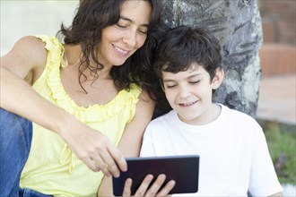 Hispanic mother and son reading digital tablet