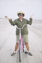 Senior woman with bicycle on beach