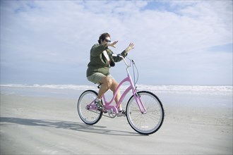 Senior woman riding bicycle on beach