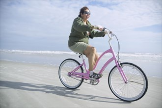 Senior Italian woman riding bicycle on beach