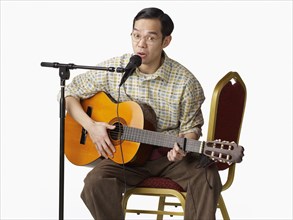 Asian man playing guitar and singing
