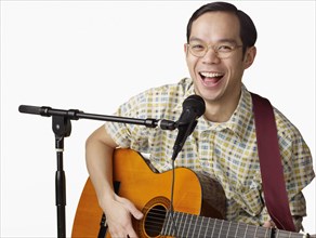 Asian man playing guitar and singing
