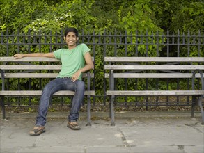 Indian man relaxing on park bench