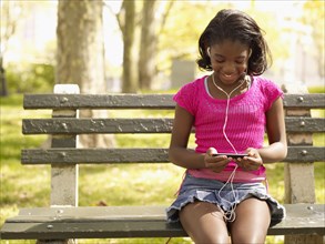 African girl listening to mp3 player in park