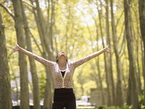 Mixed race woman with arms outstretched in park