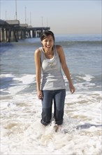 Asian woman wading near pier at beach