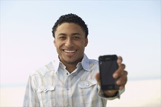 Young mixed race man showing cell phone