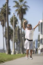 Young mixed race girl wearing sunglasses and jumping