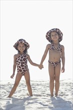 Young mixed race girls holding hands at beach