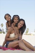 Young mixed race girls with mother at beach