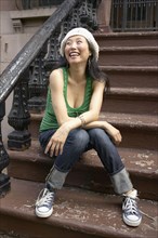 Asian woman sitting on front steps