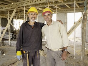Hispanic workers hugging at construction site