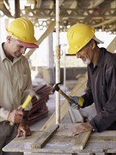 Hispanic workers using hammers at construction site