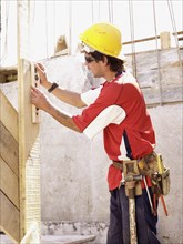 Hispanic worker using level on construction site