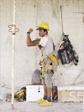 Hispanic worker flexing biceps on construction site
