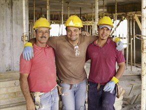 Hispanic workers hugging on construction site
