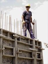 Hispanic worker standing on top of wall on construction site