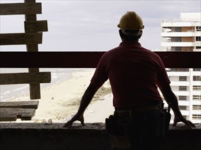 Hispanic worker looking down from construction site