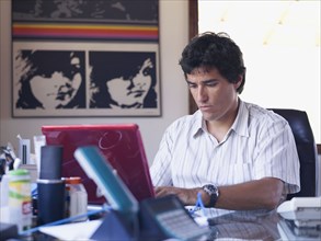 Hispanic man sitting a desk using laptop