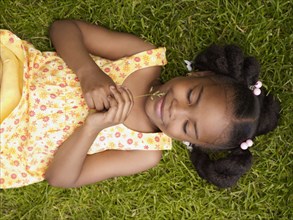 African girl laying in grass with eyes closed