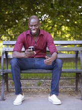 Smiling African man looking down at cell phone