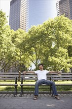 Mixed race man smiling on park bench