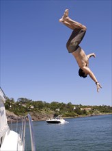 Hispanic man jumping from sailboat