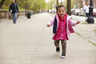 Mixed race baby girl walking on sidewalk