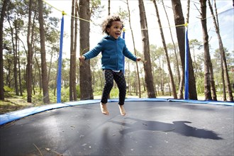 Mixed race girl jumping on trampoline