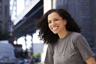Mixed race woman smiling under urban bridge
