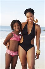Black mother and daughter smiling on beach