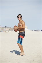 Man playing with football on beach