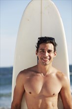 Smiling man with surfboard on beach