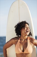 Mixed race woman holding surfboard on beach
