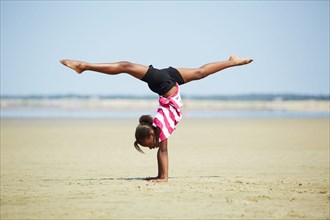 Black girl doing handstand on beach