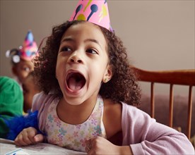 Shouting girl wearing party hat with mouth open