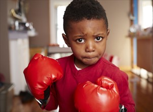 Black boy posing with boxing gloves in living room