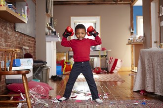 Black boy posing with boxing gloves in messy living room