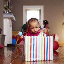 Mixed race girl opening gift in living room