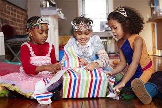Girls with tiaras opening gifts at party