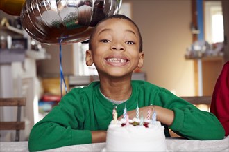 Black boy smiling with balloon and cake at party