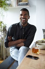 Black man with tea and cell phone at table