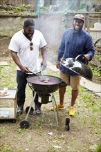 Black men grilling hamburgers at backyard barbecue