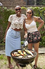 Women grilling vegetables at backyard barbecue