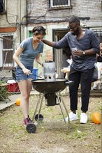 Couple lighting charcoal for backyard barbecue