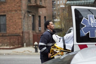 Mixed race paramedic loading patient into ambulance