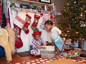 Mixed race children opening Christmas gifts
