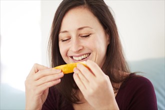 Mixed race woman eating orange