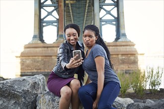 Black women posing for selfie at bridge